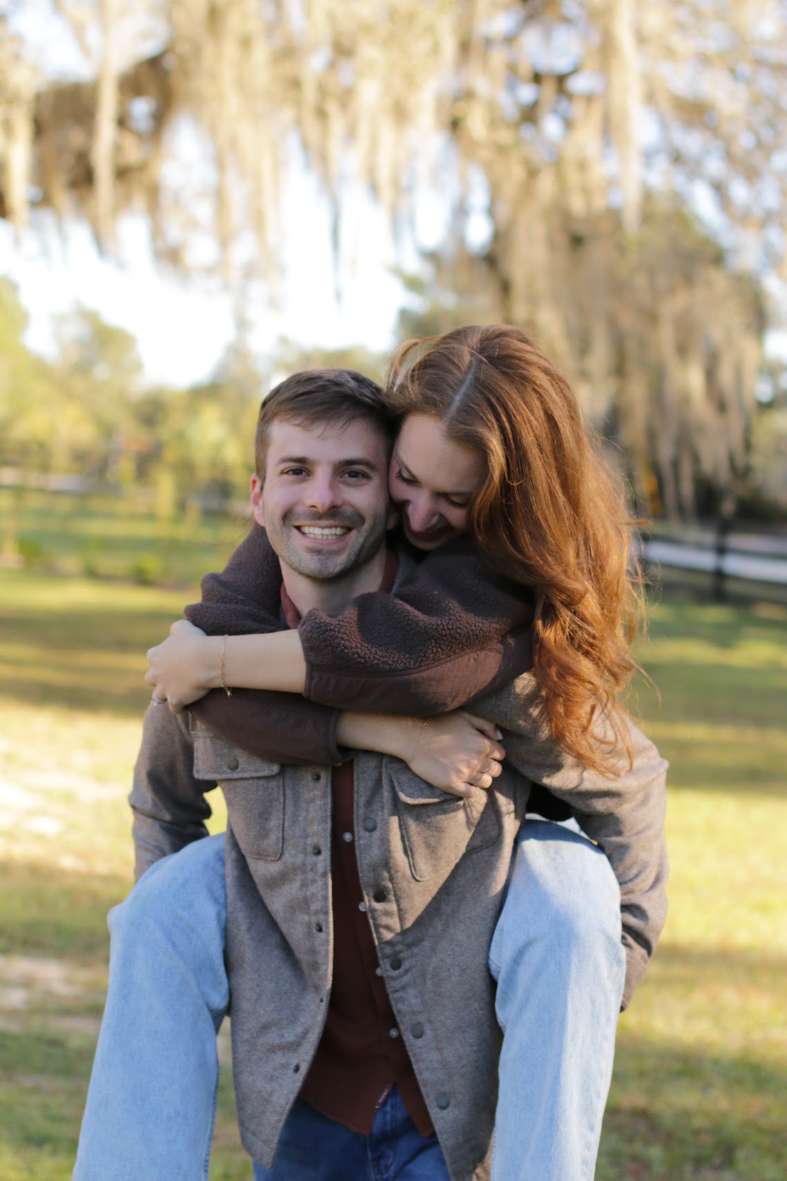 Couple piggyback under Spanish moss draped oaks